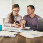 A young couple discussing their mortgage payment in front of their laptop at home.