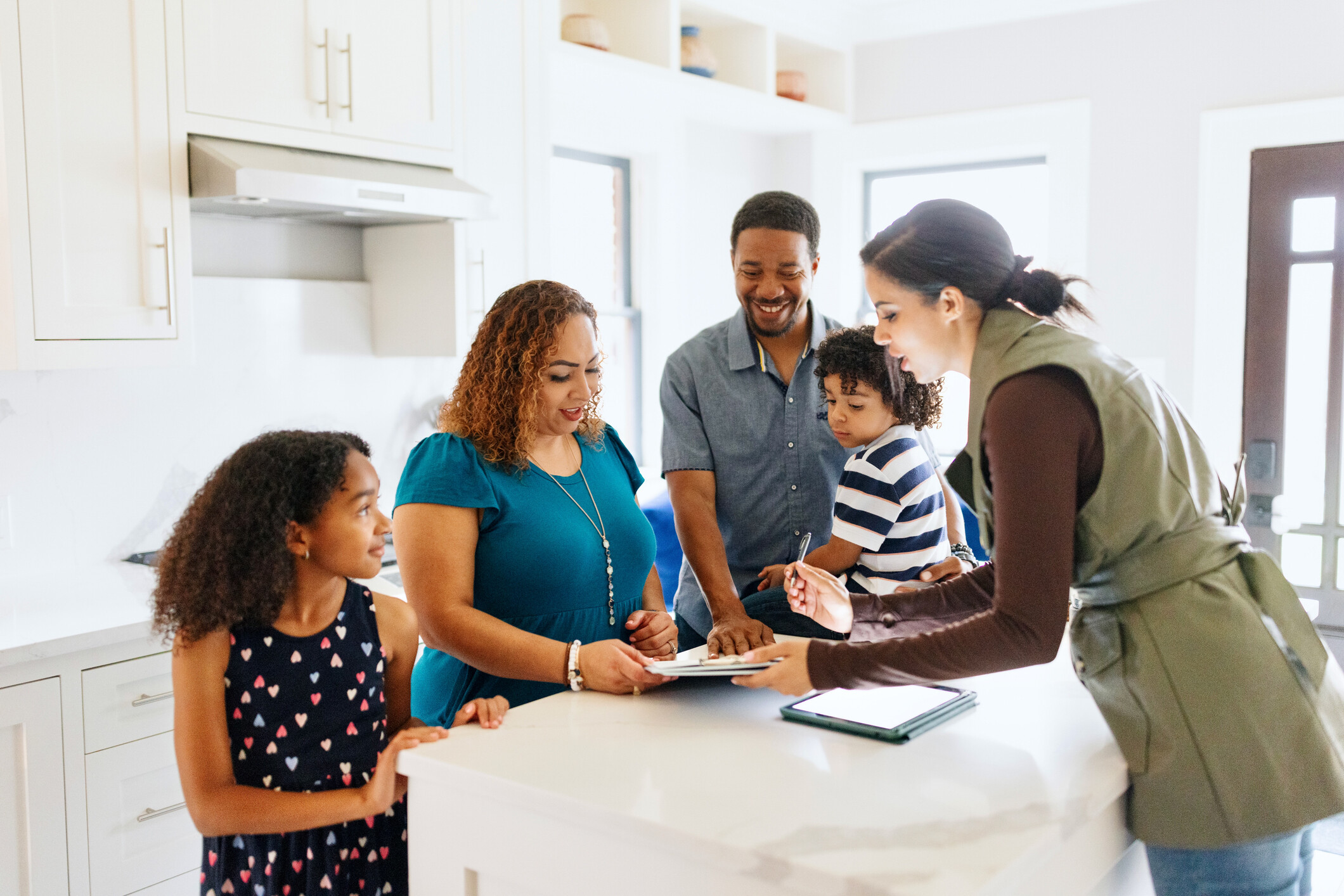 An excited family signing the agreement to buy their new house.