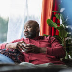 Mature man relaxing at home, looking out the window.