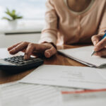 Close up of woman using calculator while filing her taxes.