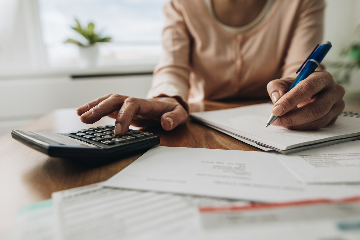 Close up of woman using calculator while filing her taxes.